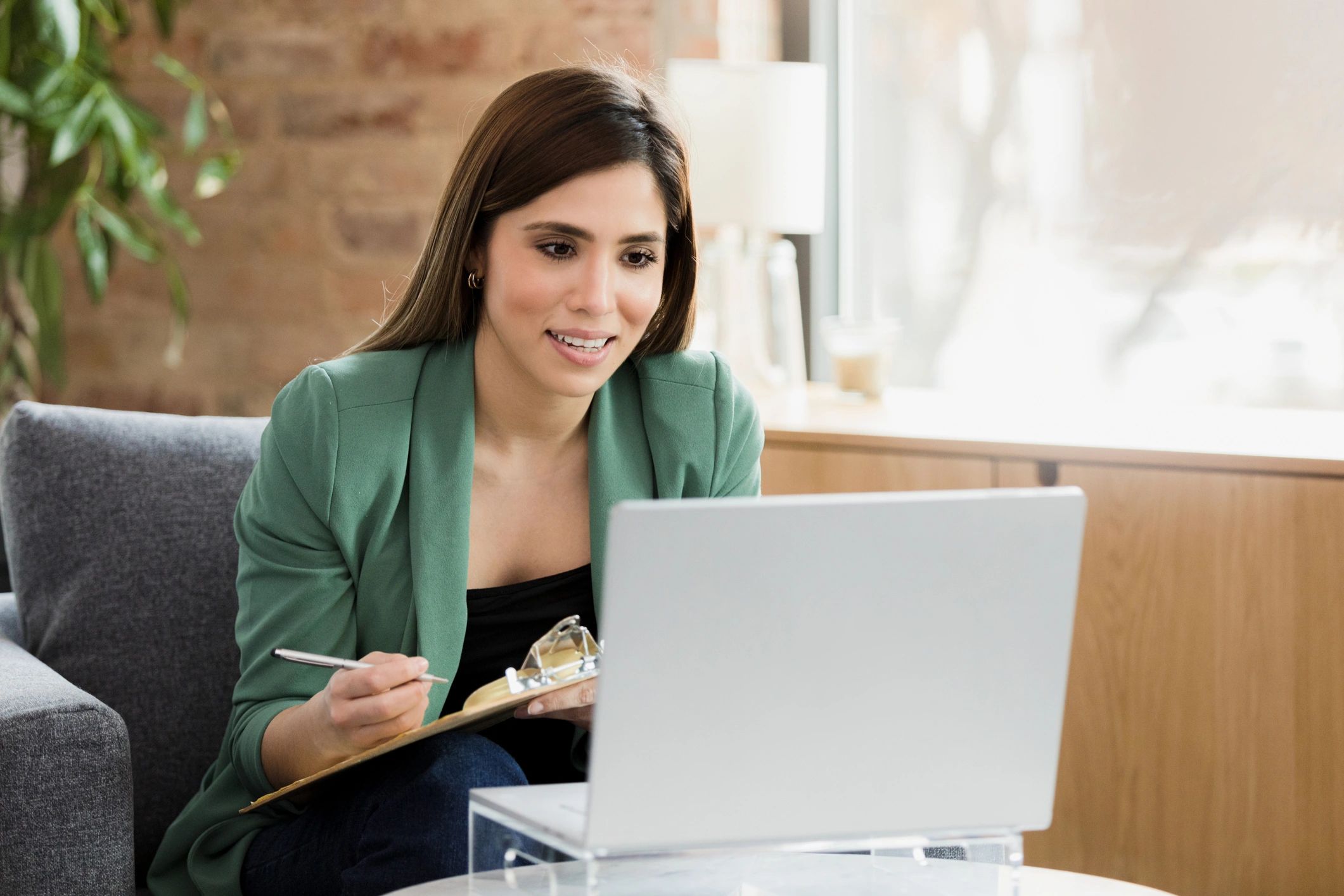Person taking notes during an online video session on a laptop